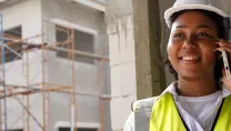 Engineer on a construction site using a phone and holding a tablet