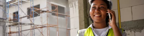 Engineer on a construction site using a phone and holding a tablet